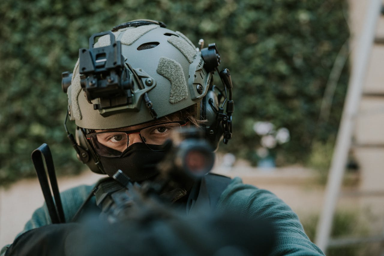Close-up of a soldier in tactical gear aiming with precision outdoors.